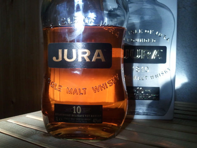 a bottle of jura sitting on a wooden table next to a card