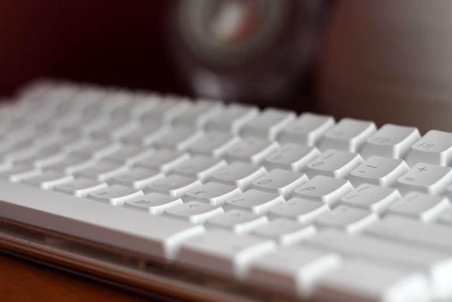 a white keyboard is sitting on a wooden desk