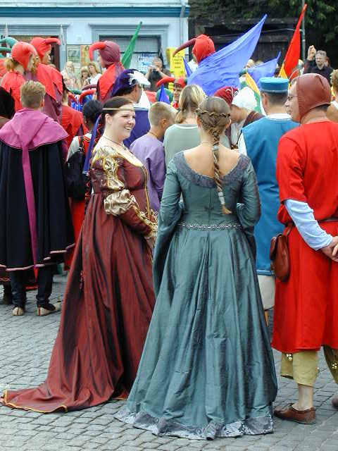 group of people wearing costumes stand in a line, all dressed in historical costume