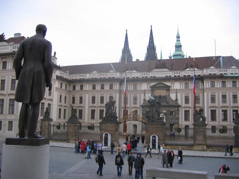 statue in front of a castle with spires and other large buildings