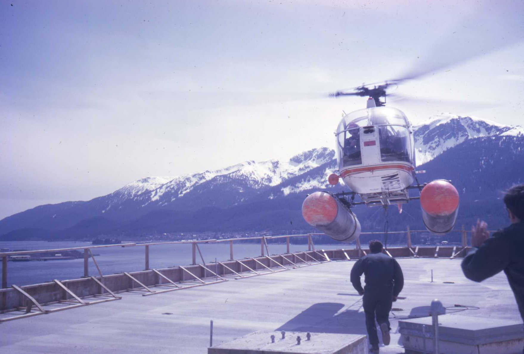 a man stands in front of a helicopter on a pier