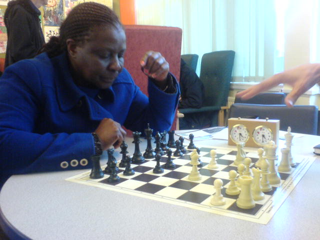 the black woman is sitting at the chess table