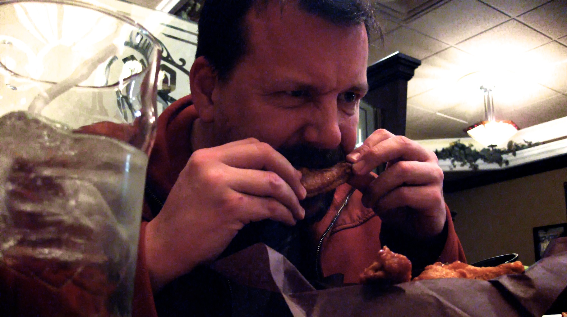 man with mustache, eating a sandwich in a restaurant