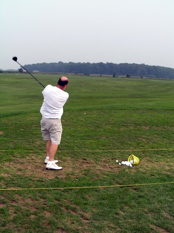 a man in white shirt playing golf and preparing to swing