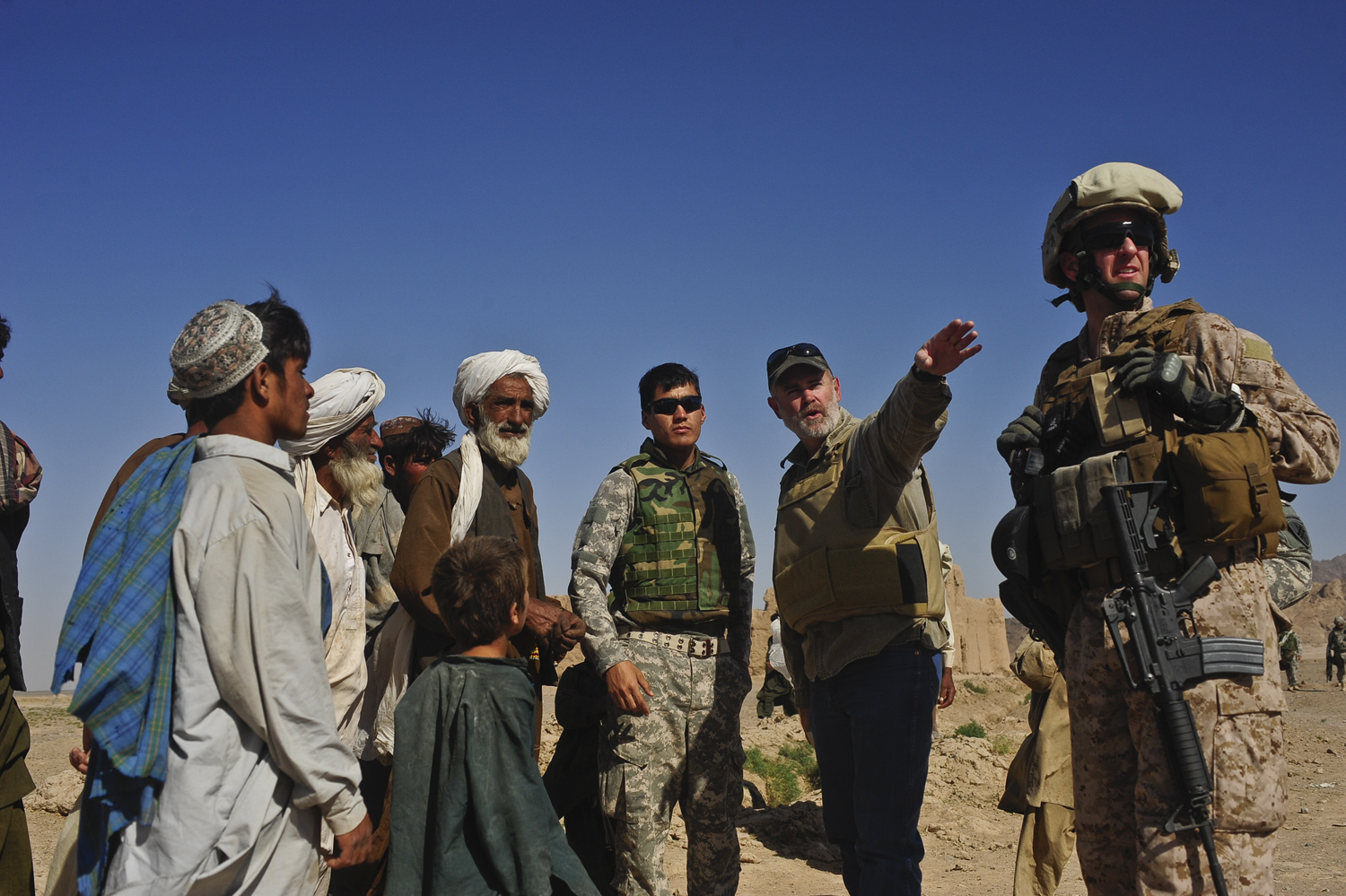 several soldiers stand in a row as one man gives soing to the other