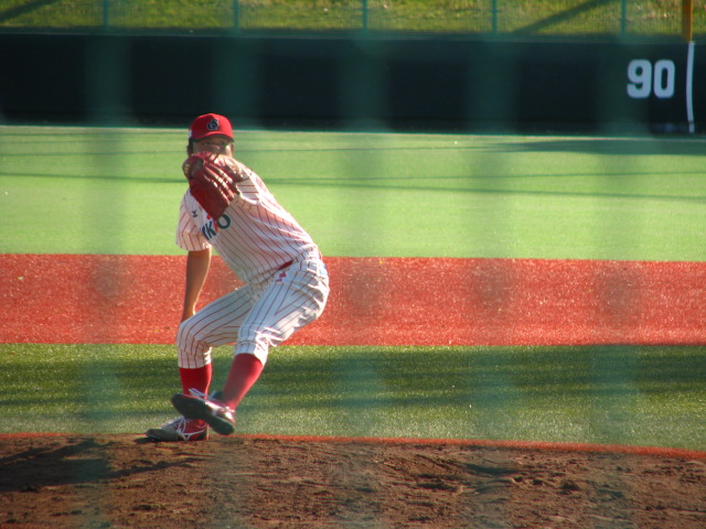 a pitcher on the mound winds up to throw a baseball