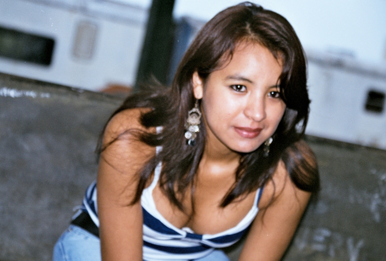 a woman in a blue and white tank top, jeans and earrings