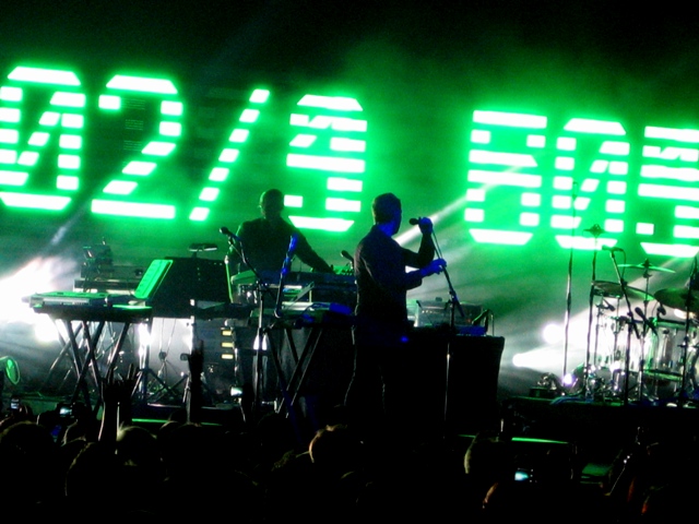 a stage with a band on the side of it that is green and has neon light