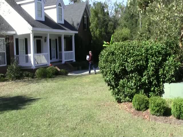 a man holding a tennis racket walking towards a house