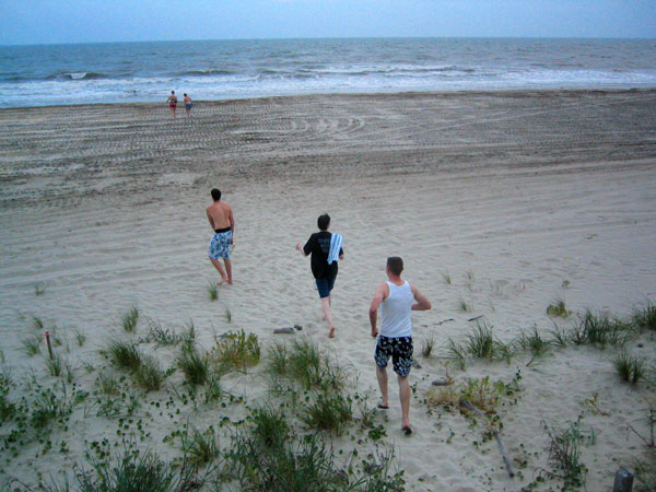 four men running on the beach at dusk