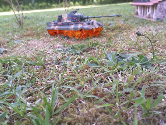 a tank laying in the grass by some bushes