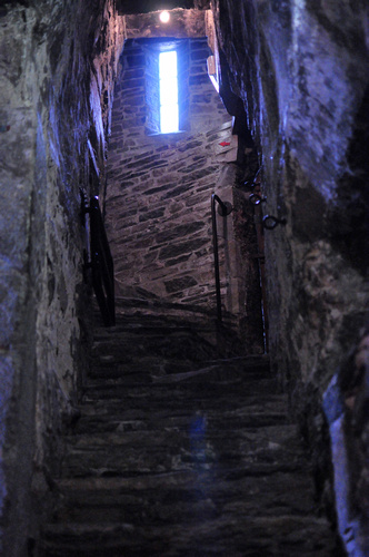 a dark narrow alley with stairs leading to bright light