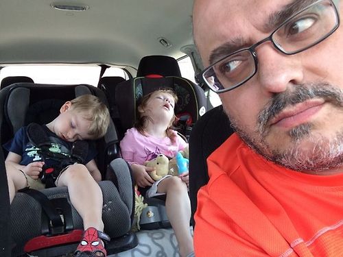 a man sitting in the back seat of a car with three s sleeping
