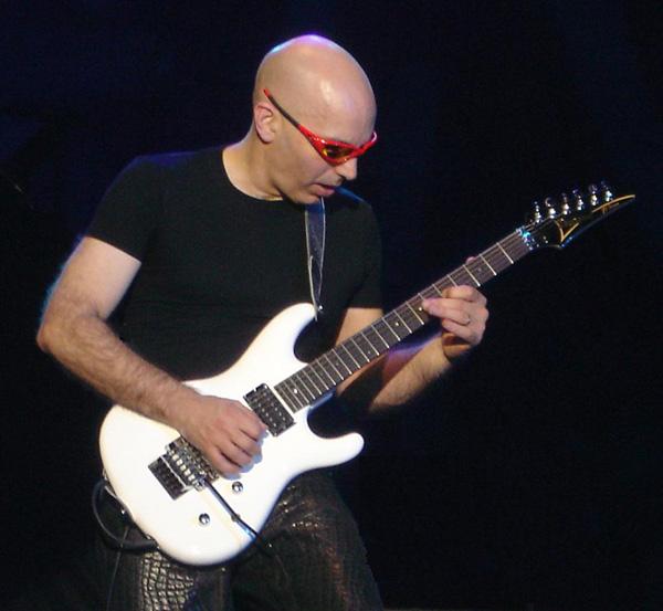 a bald man is playing a white guitar