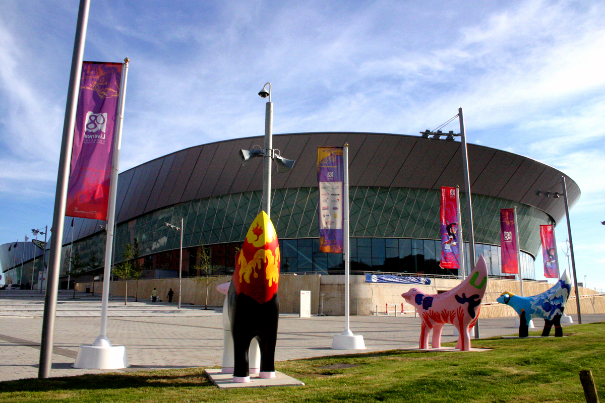 several flags and statues in front of a large circular building