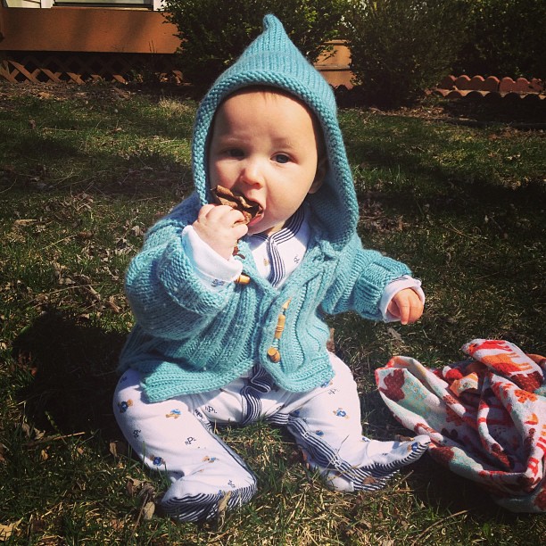 a baby sitting in the grass with food in his mouth