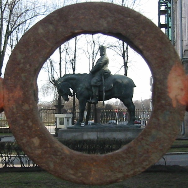 a view through an old iron ring of a statue of a man on a horse