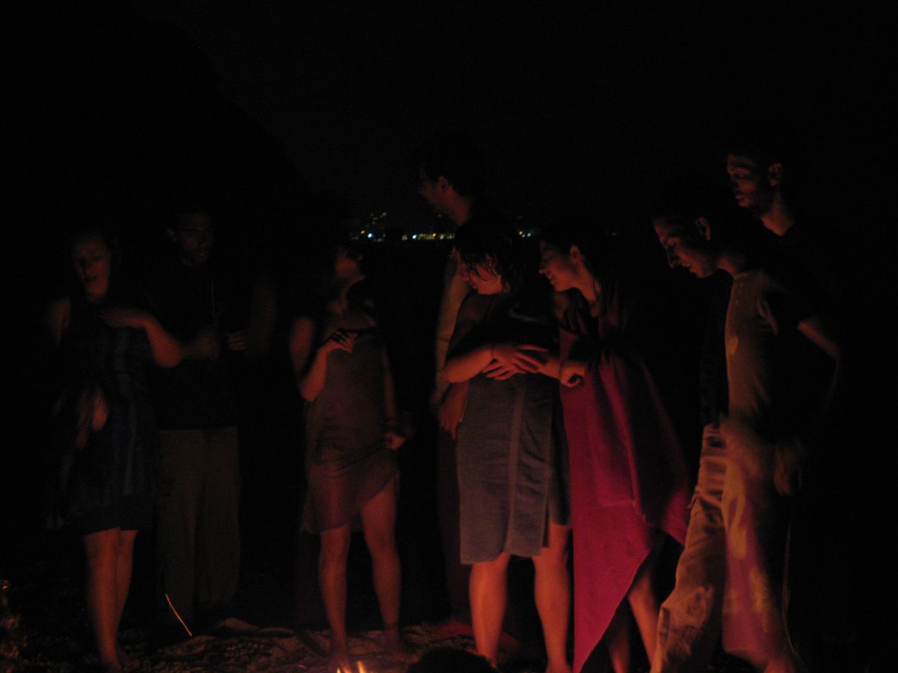 a group of people stand together around a camp fire