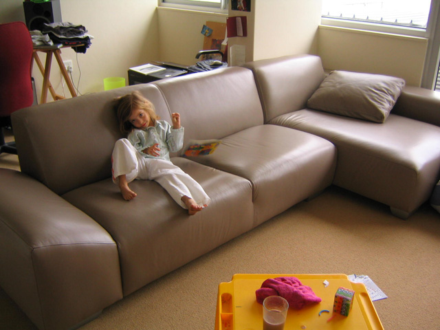 a young child sitting on a couch and a tray of food