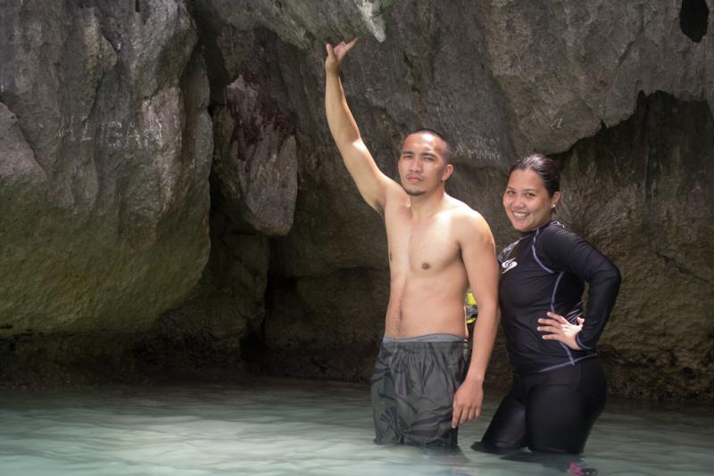a man and a woman in the water next to large rock