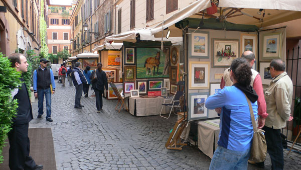 a group of people standing around an art stall on a city street
