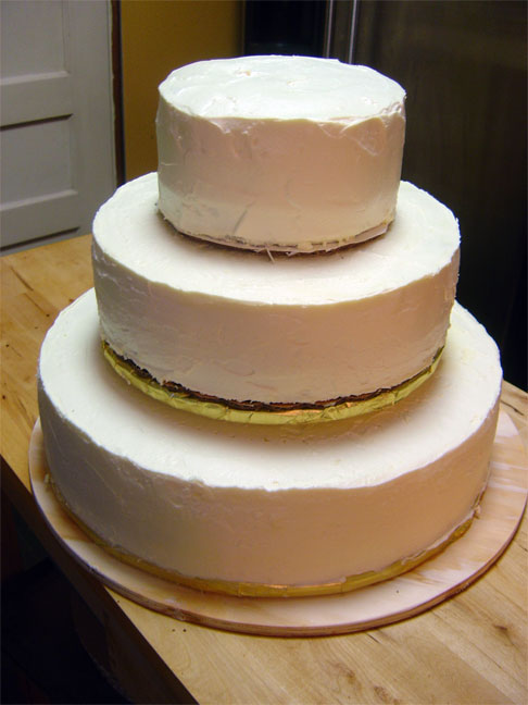 a three tiered cake sitting on top of a wooden table
