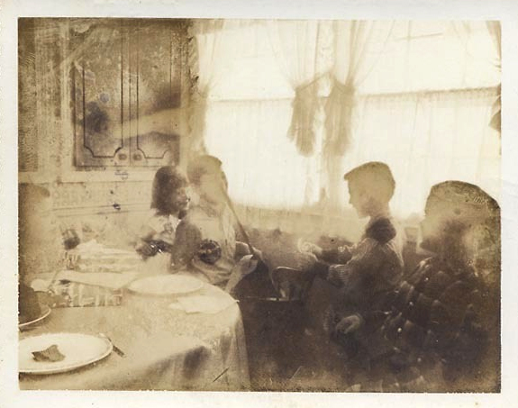 an old pograph of people at a table eating