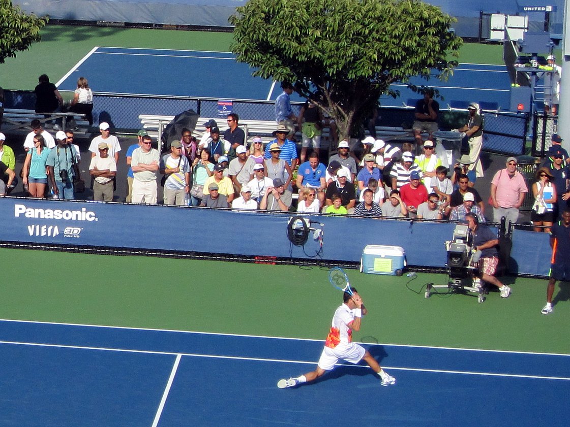 a crowd watches as a player holds up a racket
