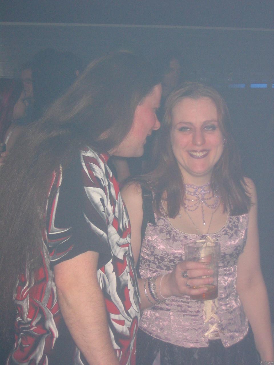 two girls standing together with one holding a glass