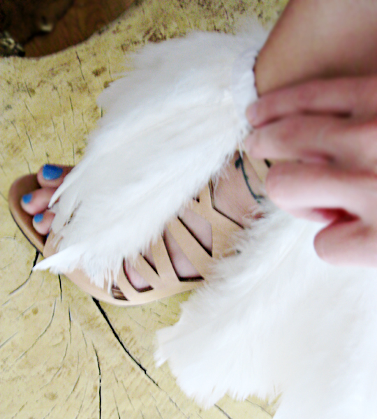 an open womans foot with a pair of white feather sandals