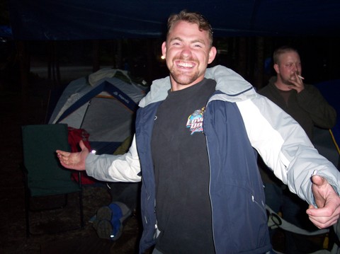 man standing in a tent smiling and pointing at camera