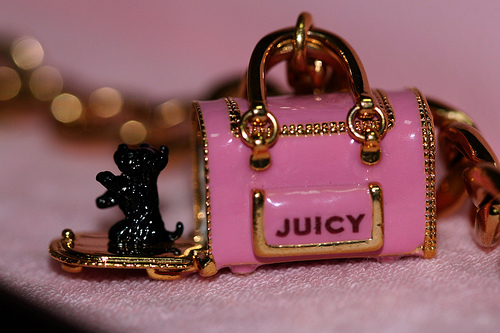 a close up of a small pink purse with black cat and dog charms