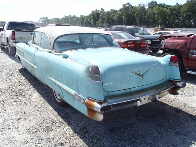 the blue car sits among other cars in a parking lot