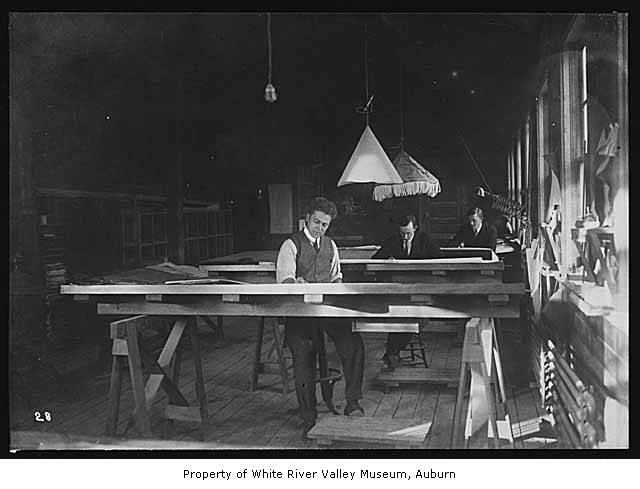 two boys are writing on long tables in the dark