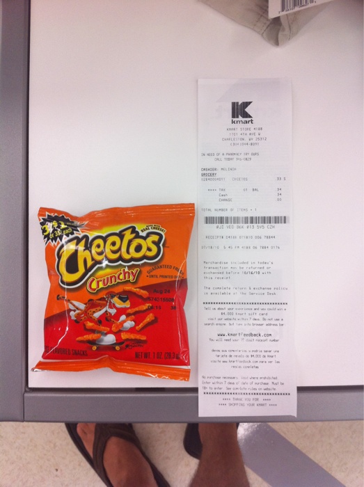 a bag of cheetos sits on the counter next to a receipt