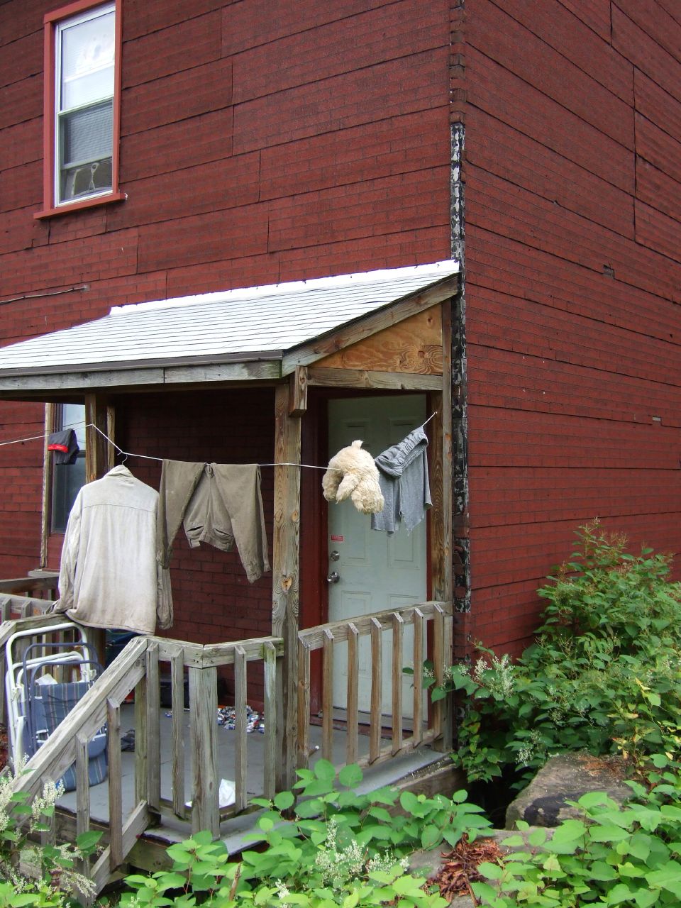 clothes hanging on clothes lines outside an outhouse