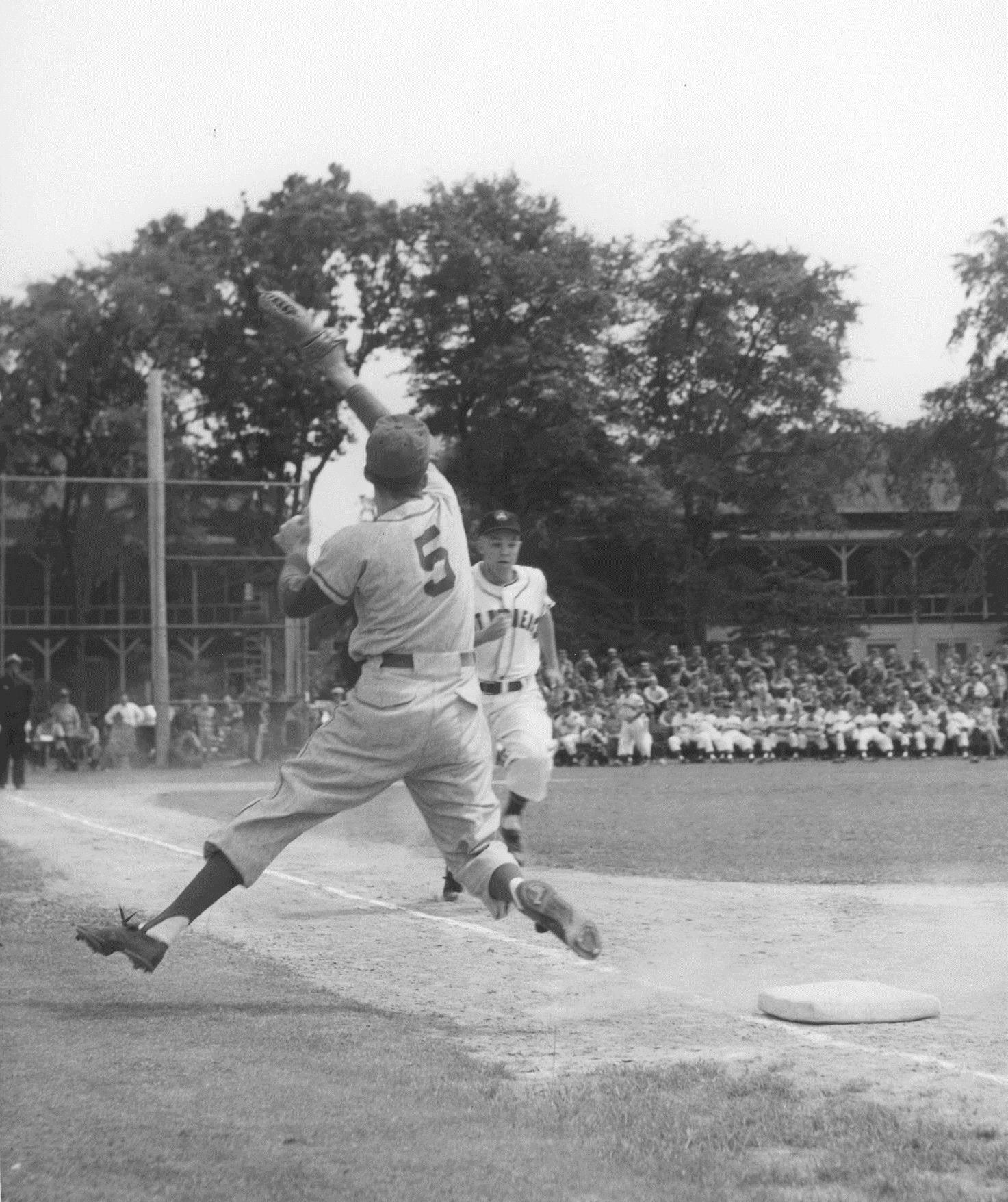 a baseball player pitching a ball in front of a crowd