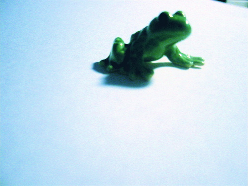 a green toy frog that is laying on its side