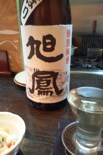 a bottle of sakeka with chopsticks and a bowl on a table