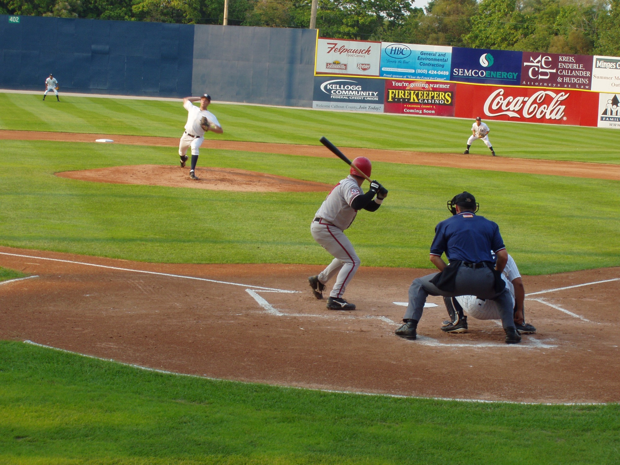 a baseball game with a batter and the pitcher throwing a pitch