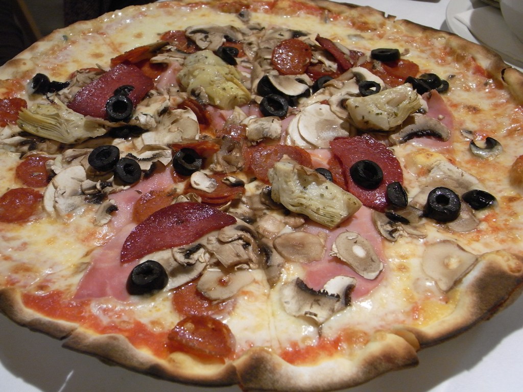 a pizza with ham, mushrooms, olives, and olives