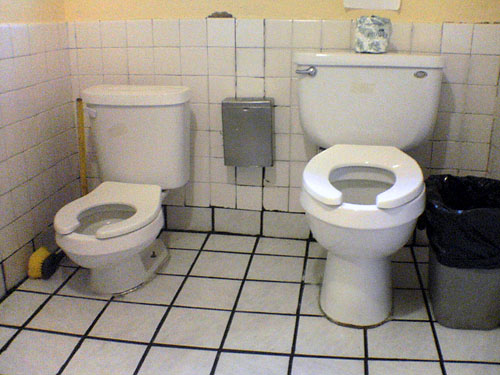 the interior of a restroom with three toilets in it