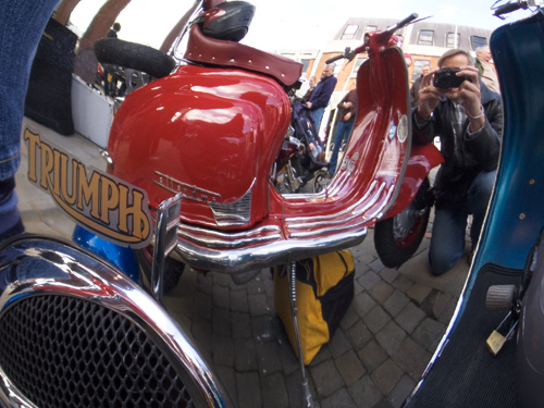 several people standing around parked motorcycles with mirrors