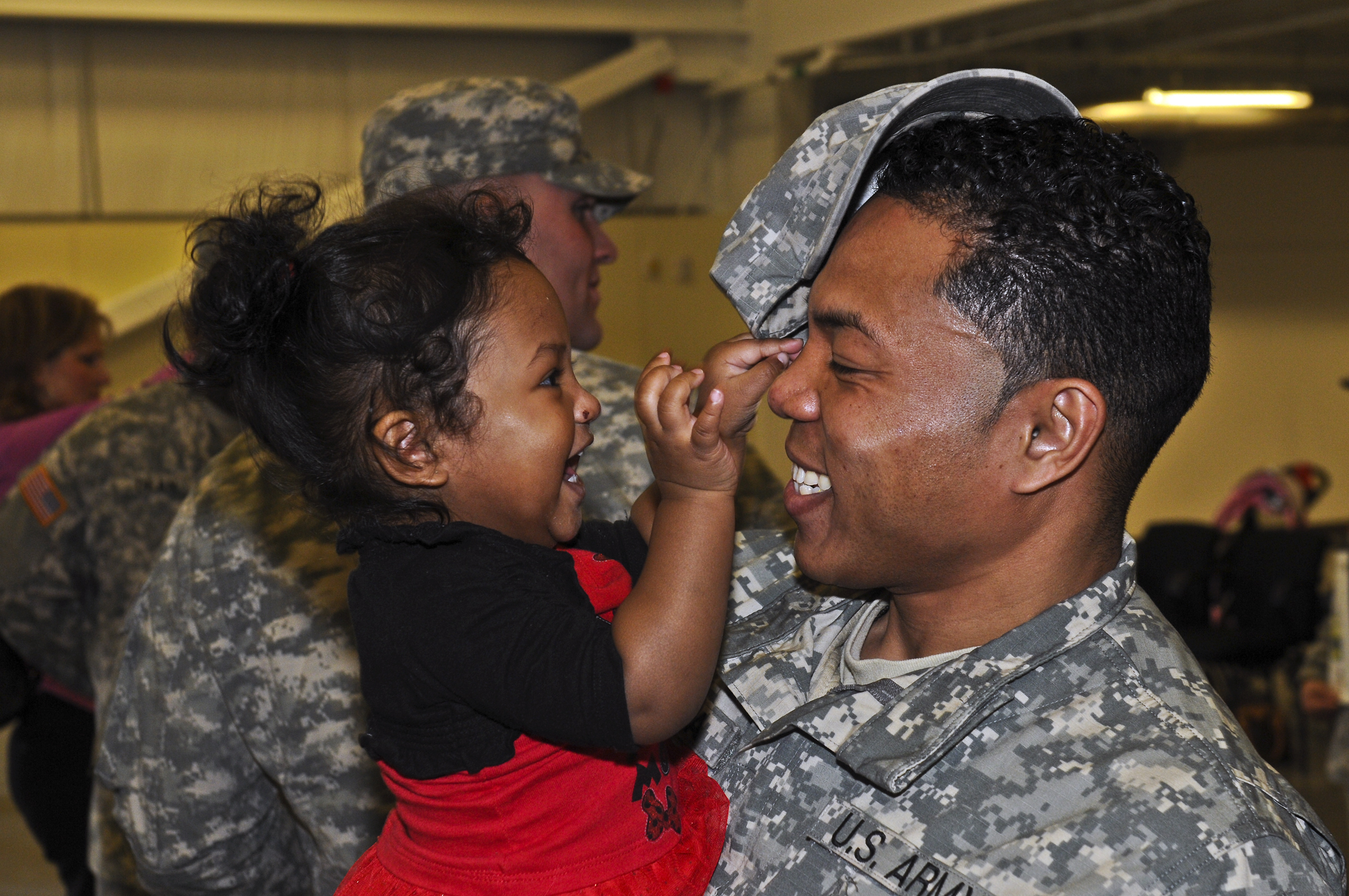 the soldier holds his daughter up for a smile