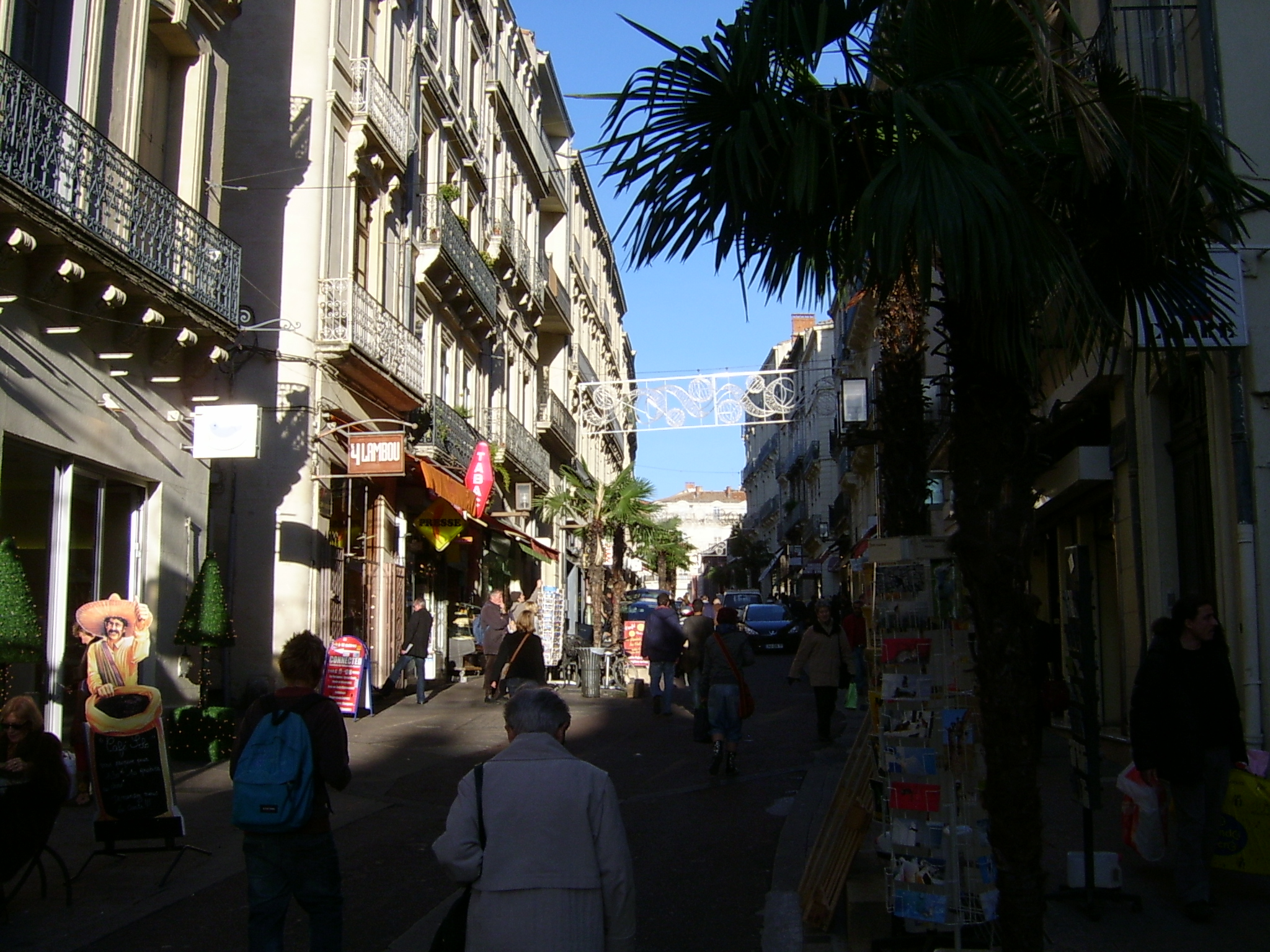 people are walking down an alley way in front of tall buildings