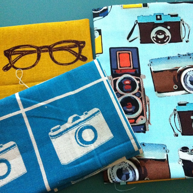 three different types of cloth with sunglasses, camera, and camera case on them