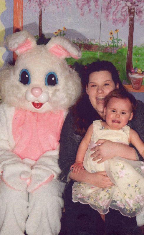 a woman holds her little girl next to an easter bunny