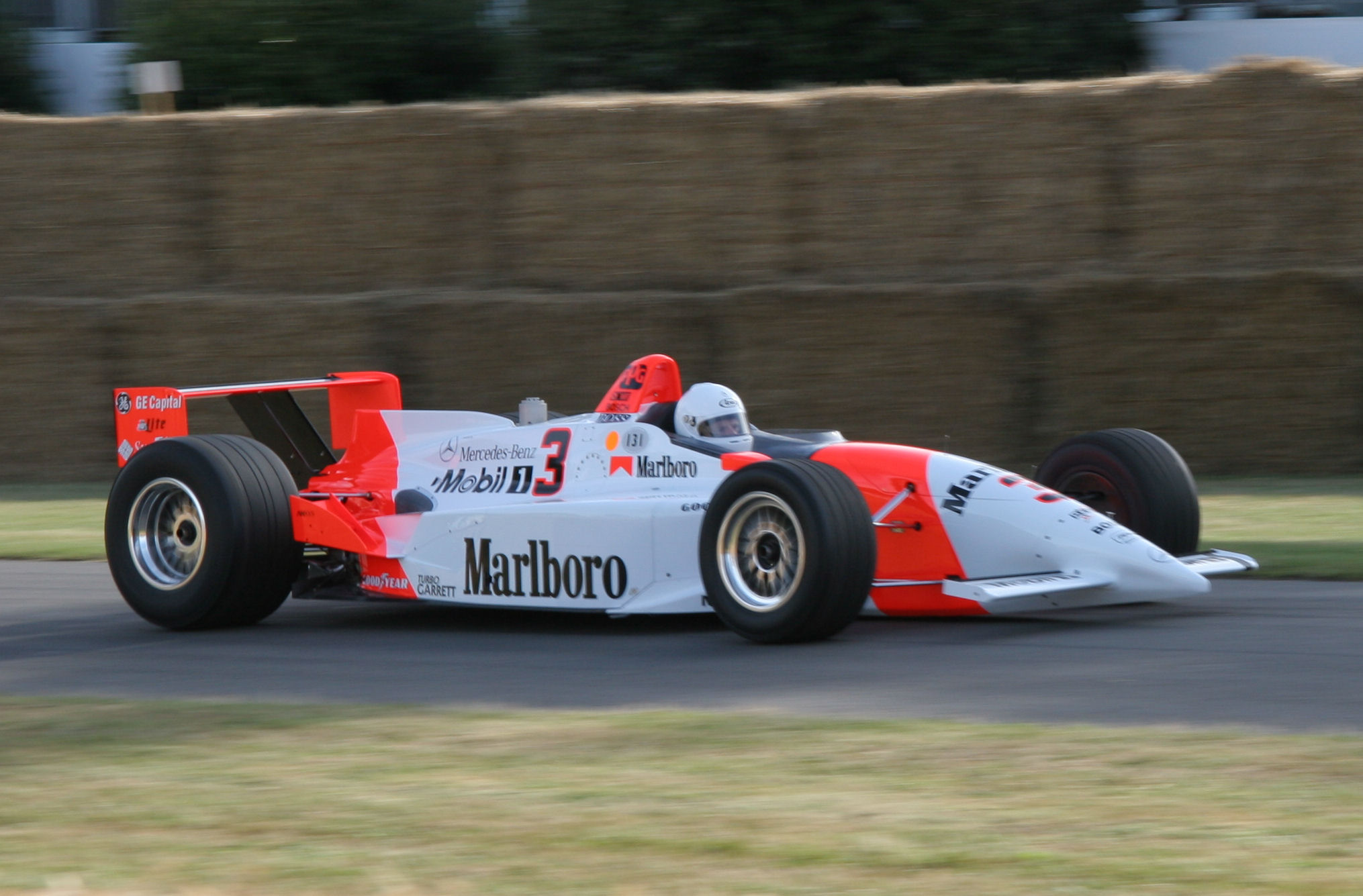 a red and white race car driving along a street