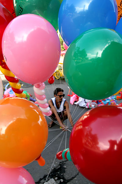 a man kneeling down with colorful balloons on his head