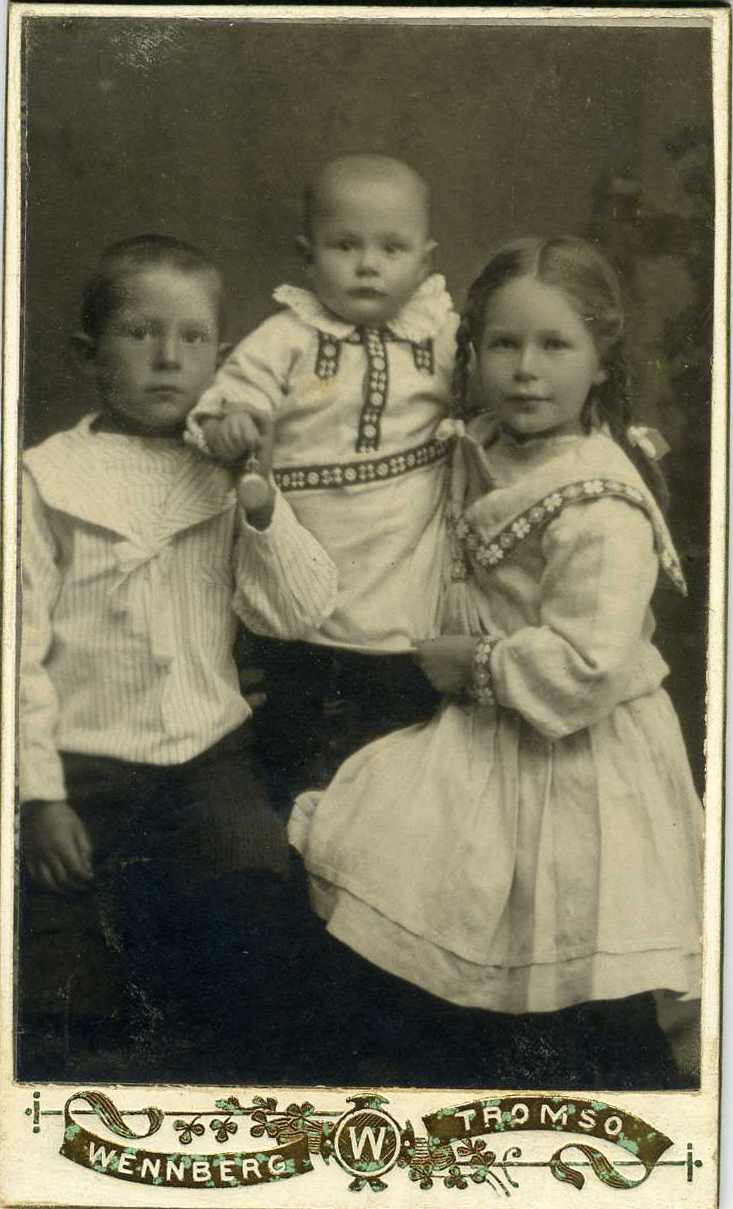 a vintage po of two children, one in a dress and the other on top of a small doll